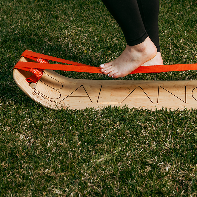 Person stepping onto an balance slackboard plus on grass