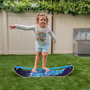 Child standing on a balance board in a backyard