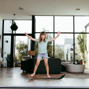 Child standing on a slackboardnin a modern living room with large windows.