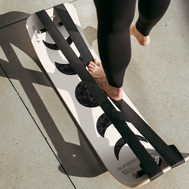 Person standing on one line of a moon slackboard plus outdoors on concrete