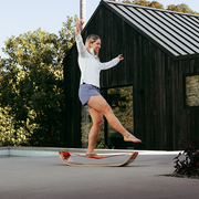 Person riding a slackboard plus outdoors near a wooden cabin
