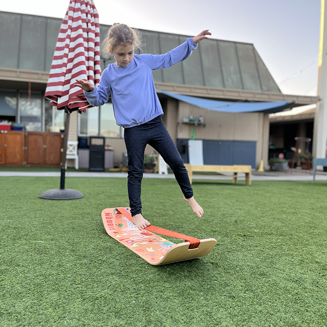 Child balancing on a unicorn slackboard outdoors