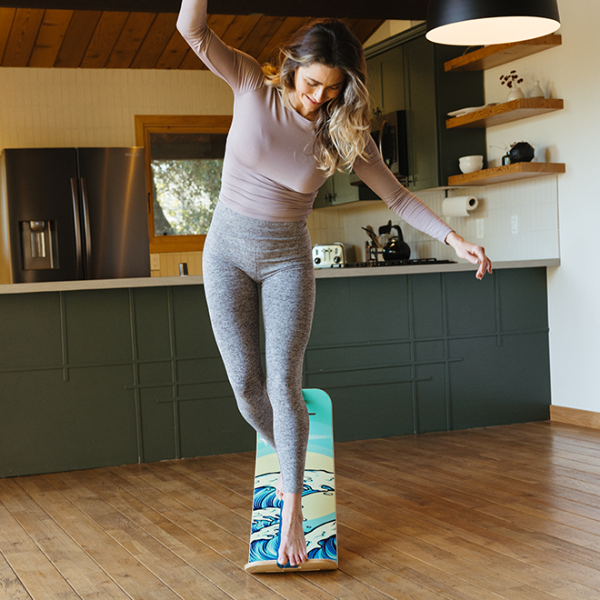 Woman standing on a waves slackboard  in a kitchen.